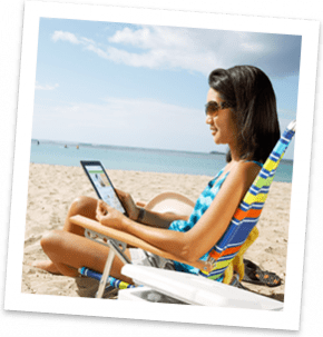 Young women sitting on beach chair at beach in swimming suit browsing the internet on a tablet device